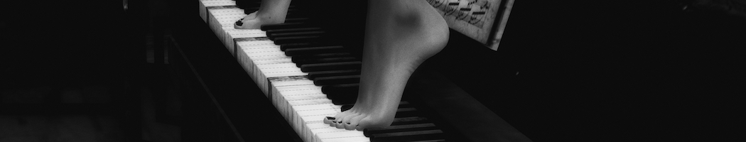 two feet standing on row of piano keys, in black and white