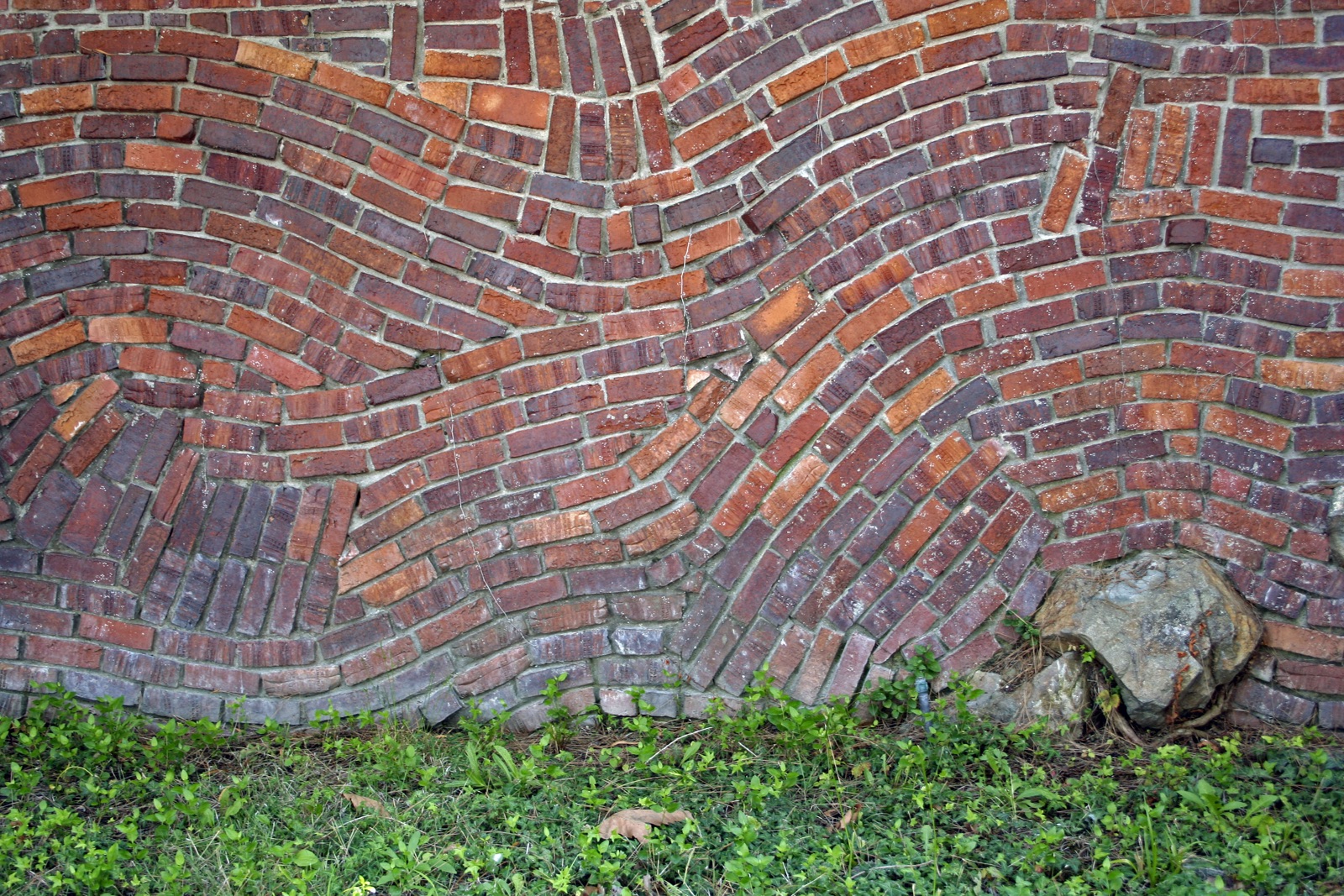 Image of a brick wall, with bricks curving in different directions.